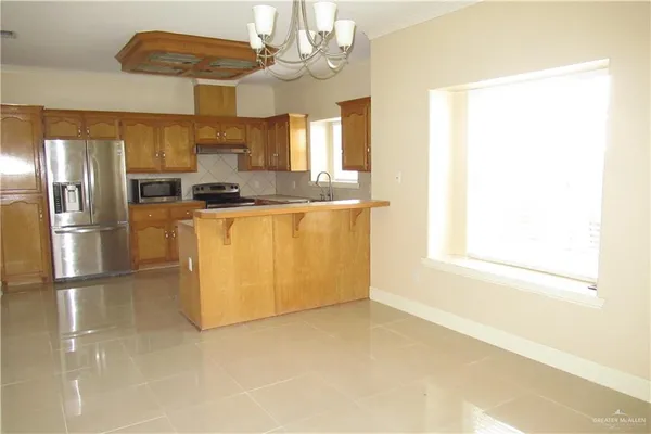 a kitchen with stainless steel appliances granite countertop a refrigerator a sink dishwasher a stove and a refrigerator