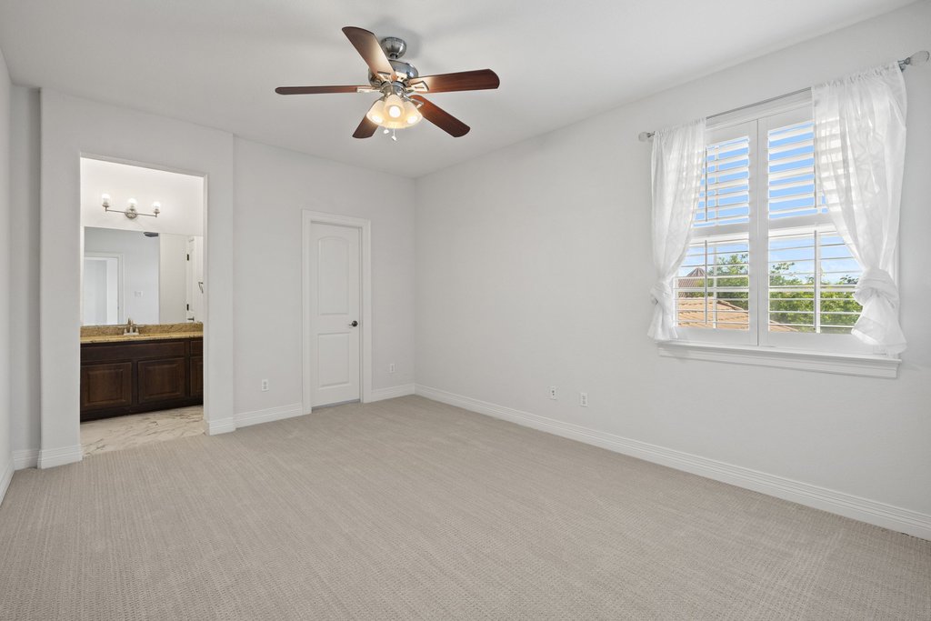 109 Largo Cove Austin, TX 78734 - Photo 26 of 40 A quiet bedroom with light carpet and a private entrance to an adjoining bathroom.