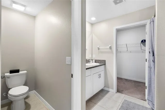a bathroom with a granite countertop toilet sink and mirror