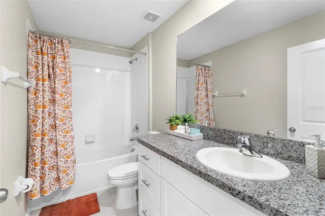 a bathroom with a granite countertop sink a toilet a mirror a vanity and shower