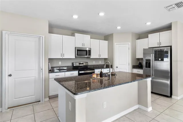 a kitchen with granite countertop a refrigerator a sink a stove a microwave a counter top space and cabinets