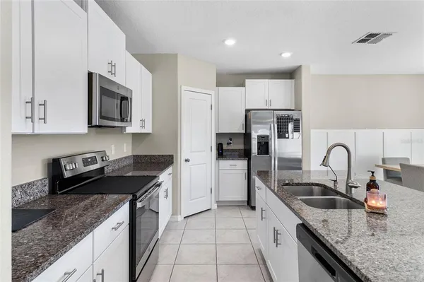 a kitchen with granite countertop a sink stainless steel appliances and white cabinets