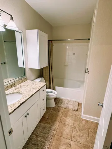 a bathroom with a granite countertop sink a toilet and shower