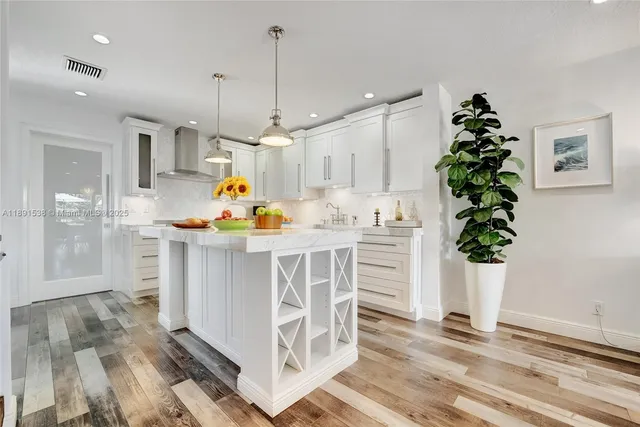 a white kitchen with white cabinets and wooden floor