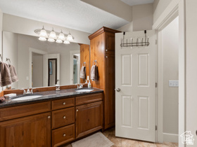 514 North Olympic Way Midway, UT 84049 - Photo 27 of 30 Bathroom featuring a dual vanity with a dark stone countertop, two undermount sinks, and wood cabinetry