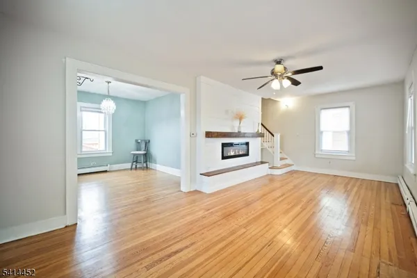 a view of a livingroom with wooden floor and a kitchen