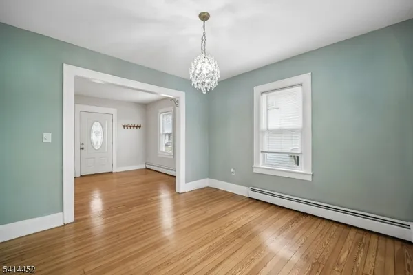 an empty room with wooden floor chandelier and windows