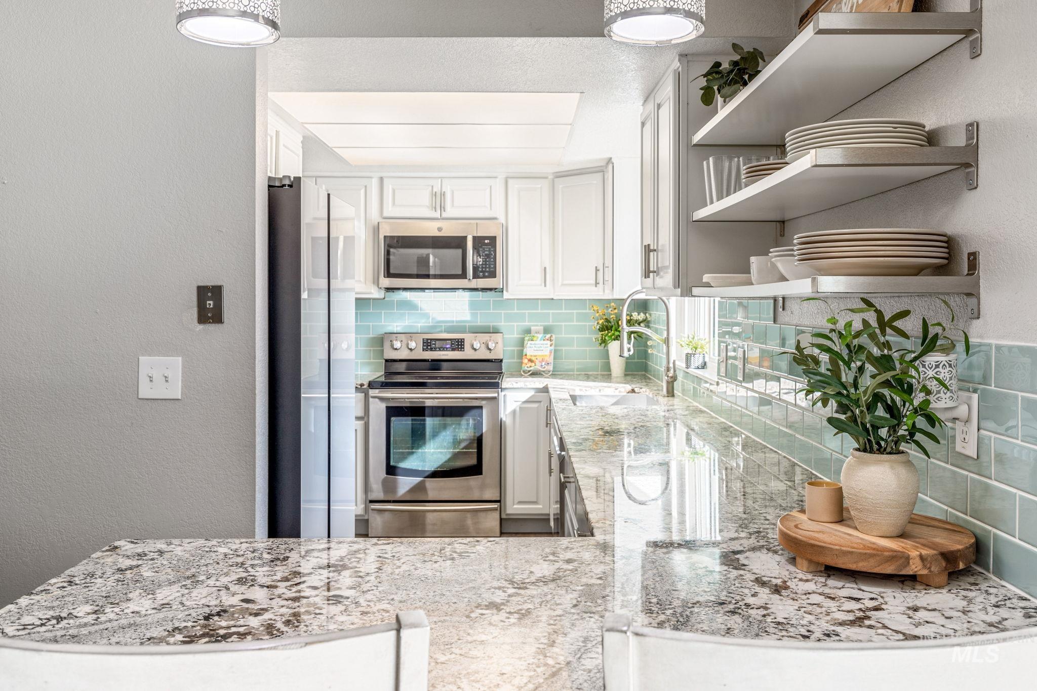 3209 Whitman Drive Boise, ID 83716 - Photo 15 of 45 Kitchen featuring open shelves, a textured wall, stainless steel appliances, white cabinets, and light stone countertops