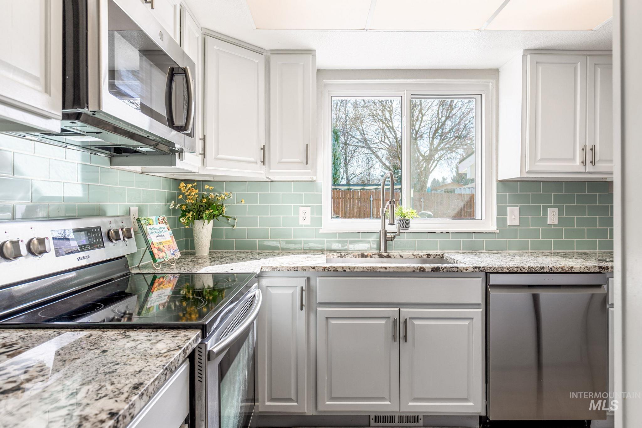 3209 Whitman Drive Boise, ID 83716 - Photo 17 of 45 Kitchen with stainless steel appliances, light stone counters, white cabinetry, and decorative backsplash