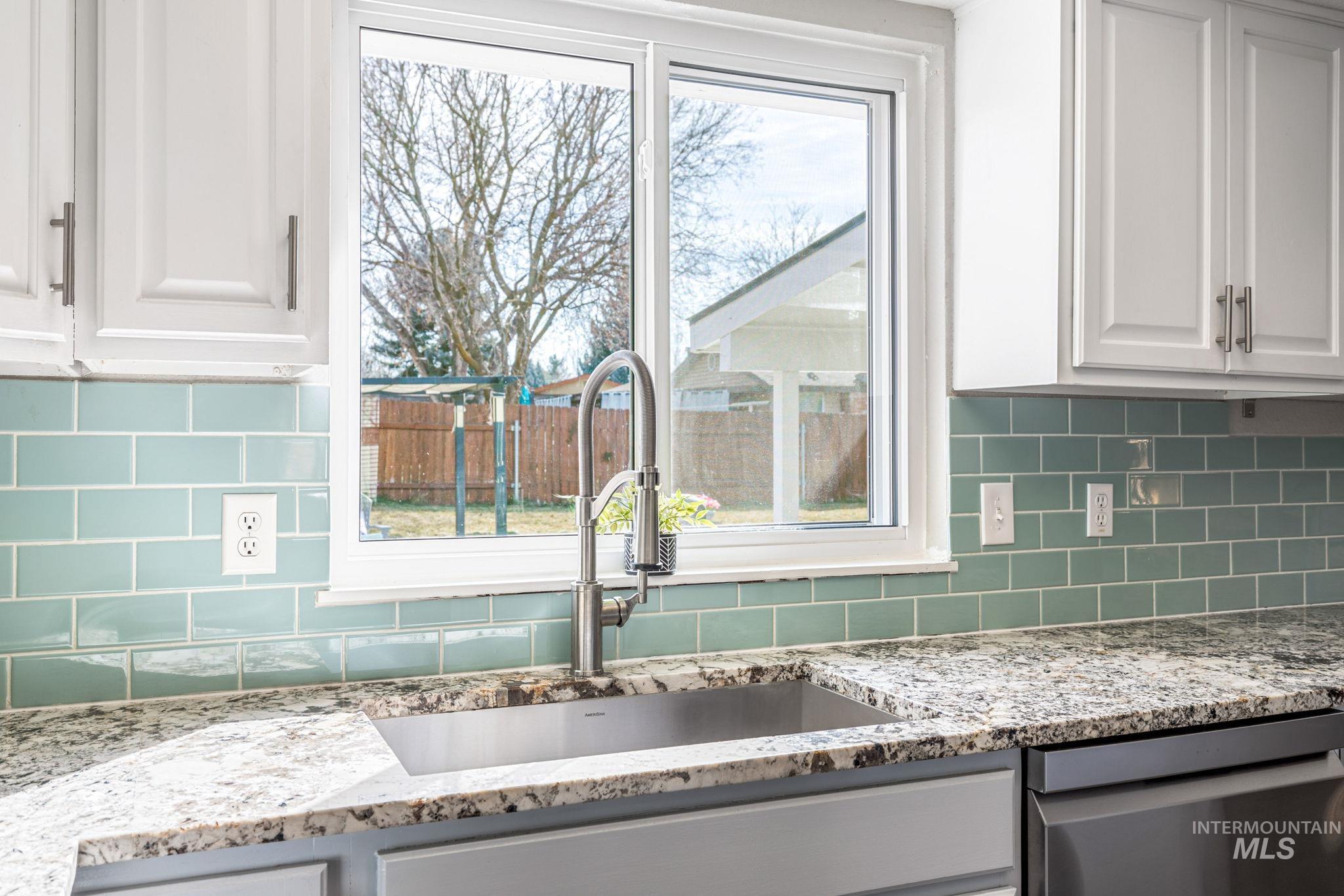 3209 Whitman Drive Boise, ID 83716 - Photo 18 of 45 Kitchen featuring light stone countertops, white cabinets, stainless steel dishwasher, and tasteful backsplash