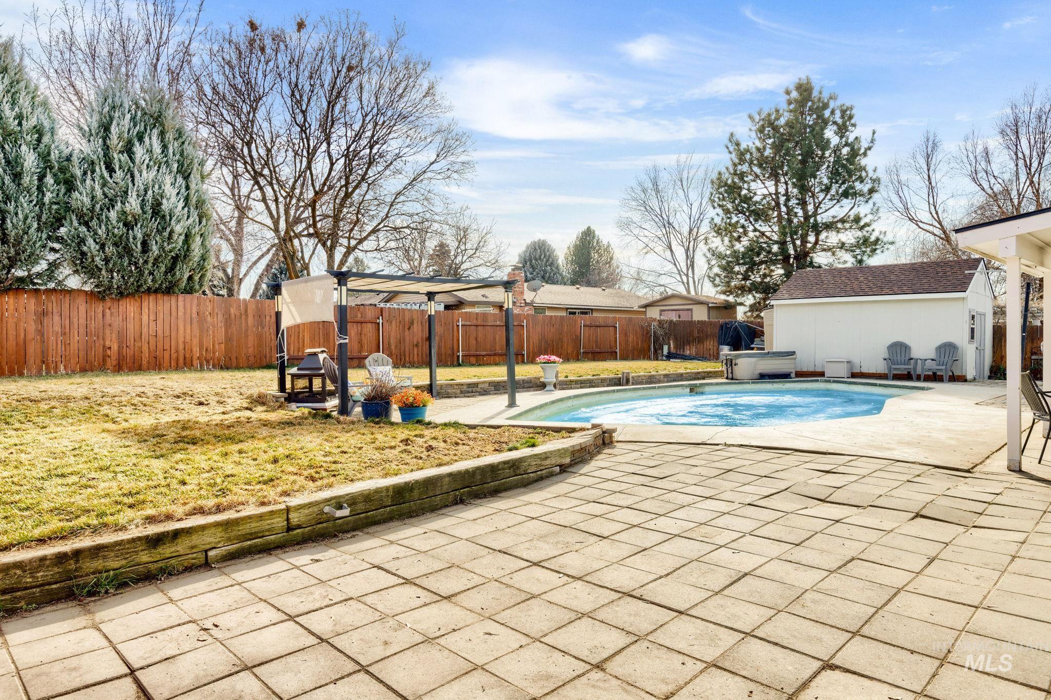 3209 Whitman Drive Boise, ID 83716 - Photo 36 of 45 View of swimming pool featuring patio surround, a fenced backyard, an outbuilding, and a hot tub