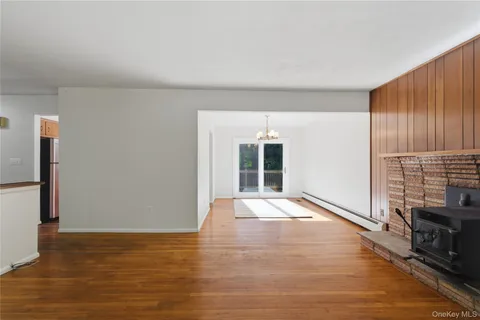 a view of an empty room with wooden floor and a fireplace