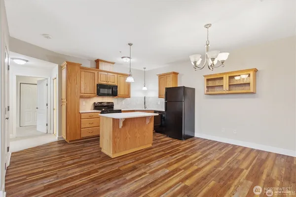 a kitchen with stainless steel appliances granite countertop a refrigerator a stove a microwave oven a refrigerator with white cabinets and wooden floor