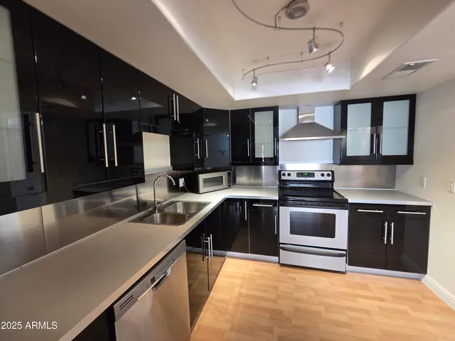 a kitchen with kitchen island granite countertop a sink counter top space cabinets and stainless steel appliances