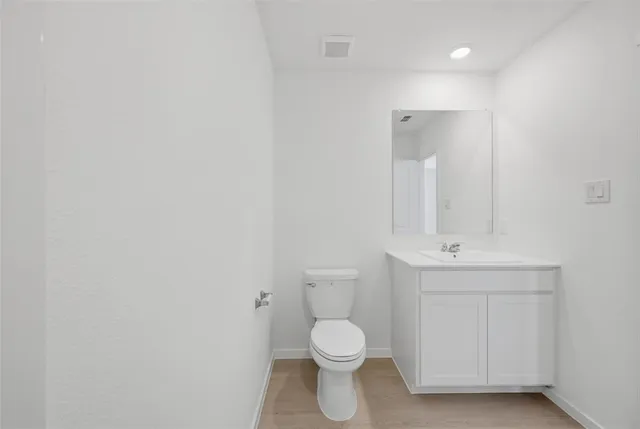 a bathroom with a toilet a sink a mirror and vanity