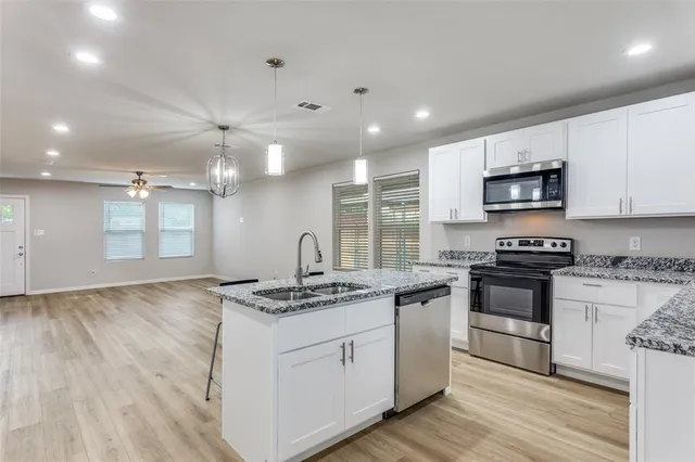 a kitchen with stainless steel appliances granite countertop a stove a sink and a microwave