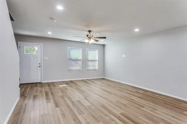 a view of an empty room with wooden floor and a window
