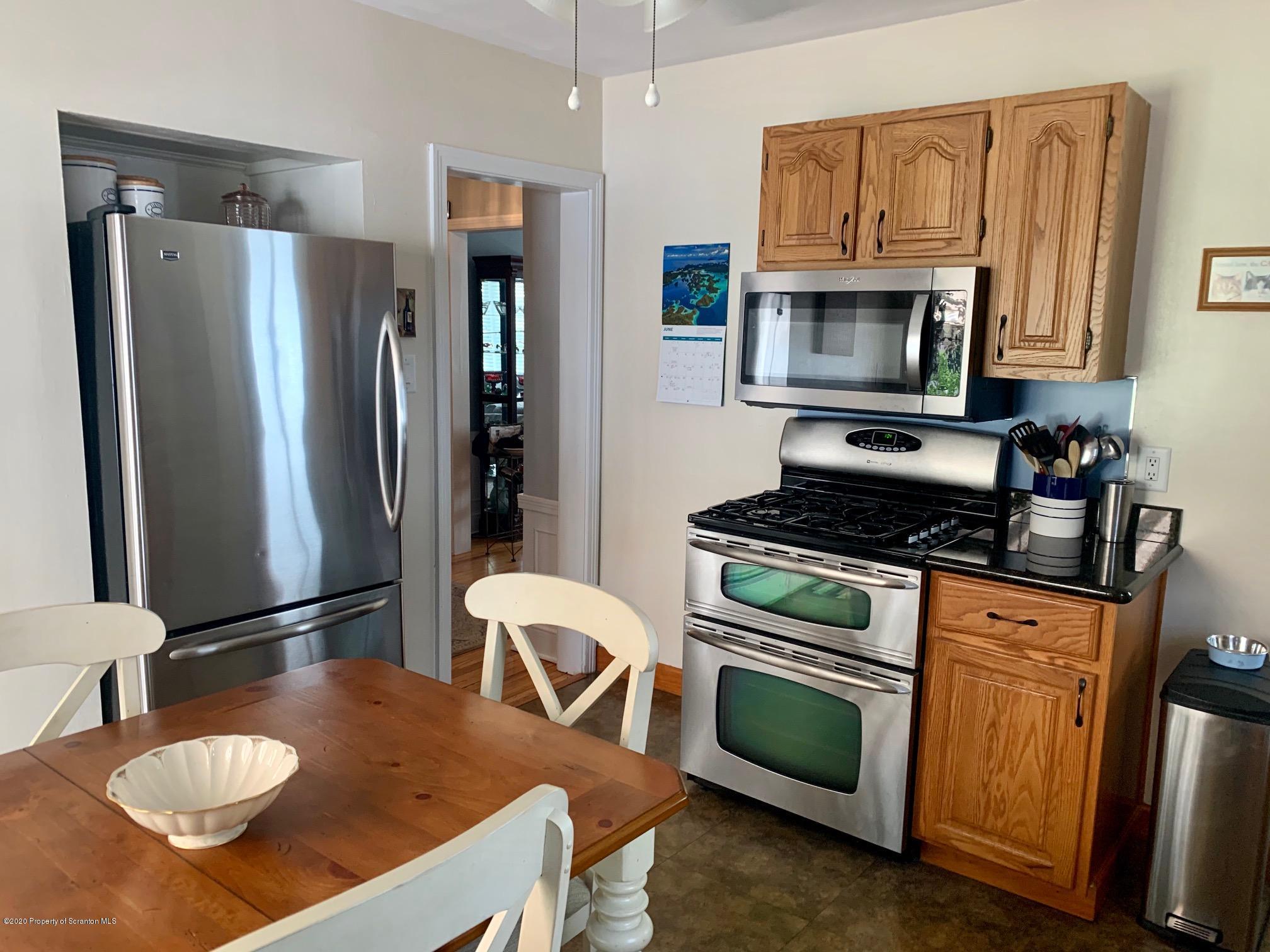 1094 Rutter Avenue Kingston, PA 18704 - Photo 10 of 35 a kitchen with stainless steel appliances granite countertop a stove a refrigerator a sink dishwasher a dining table and chairs with wooden floor