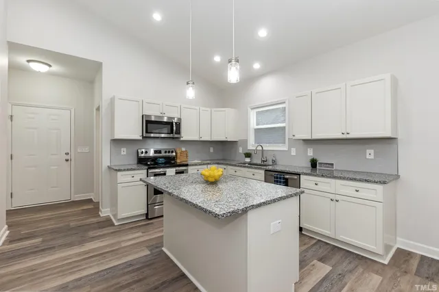 a kitchen with a stove a sink a refrigerator and cabinets
