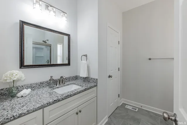 a bathroom with a granite countertop sink and mirror