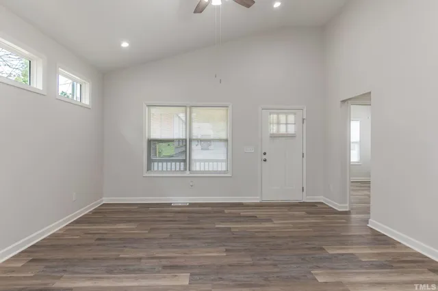 an empty room with wooden floor and windows
