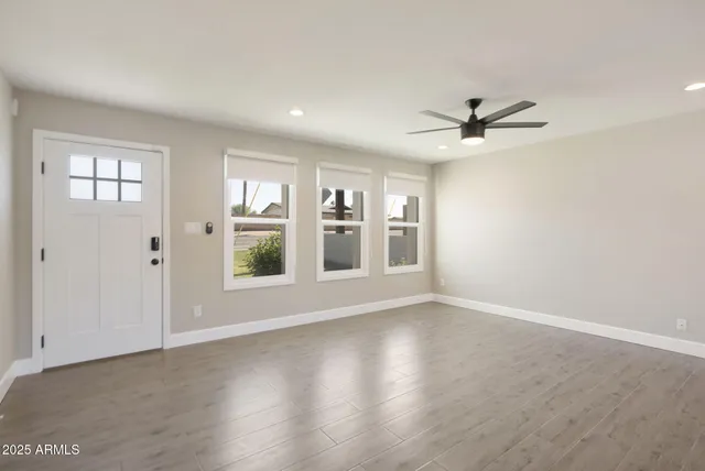 a view of an empty room with a window and wooden floor