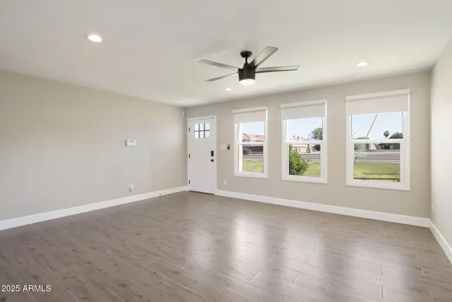 a view of an empty room with a window and wooden floor