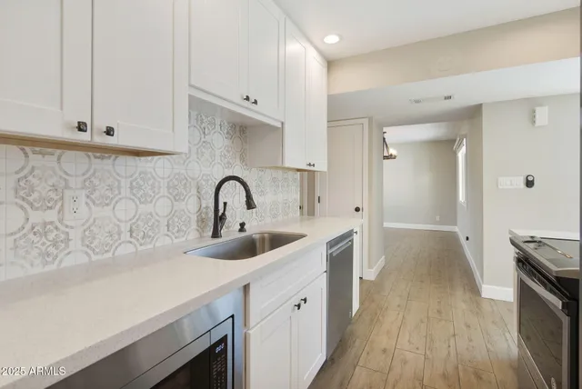 a view of a kitchen with a sink and dishwasher with wooden floor