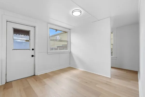 a view of an empty room with wooden floor and a window
