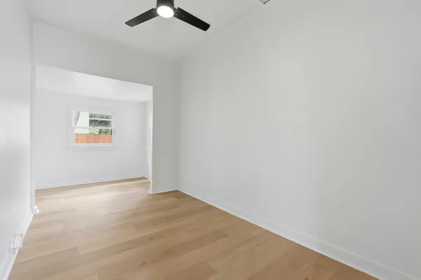an empty room with windows and fan