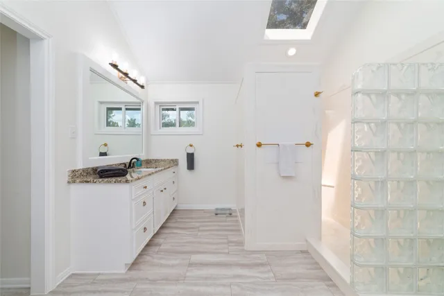a bathroom with a granite countertop shower a sink and a mirror