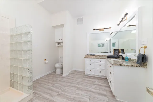 a spacious bathroom with a granite countertop sink a toilet and a shower