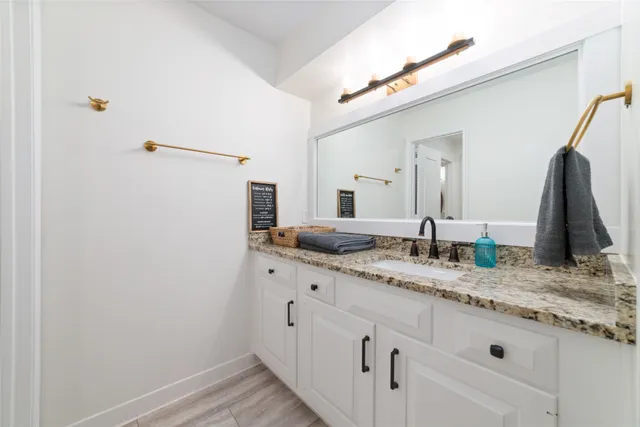 a bathroom with a granite countertop sink and a mirror