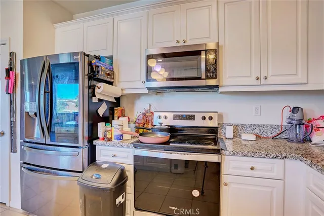 a kitchen with stainless steel appliances granite countertop a refrigerator and white cabinets