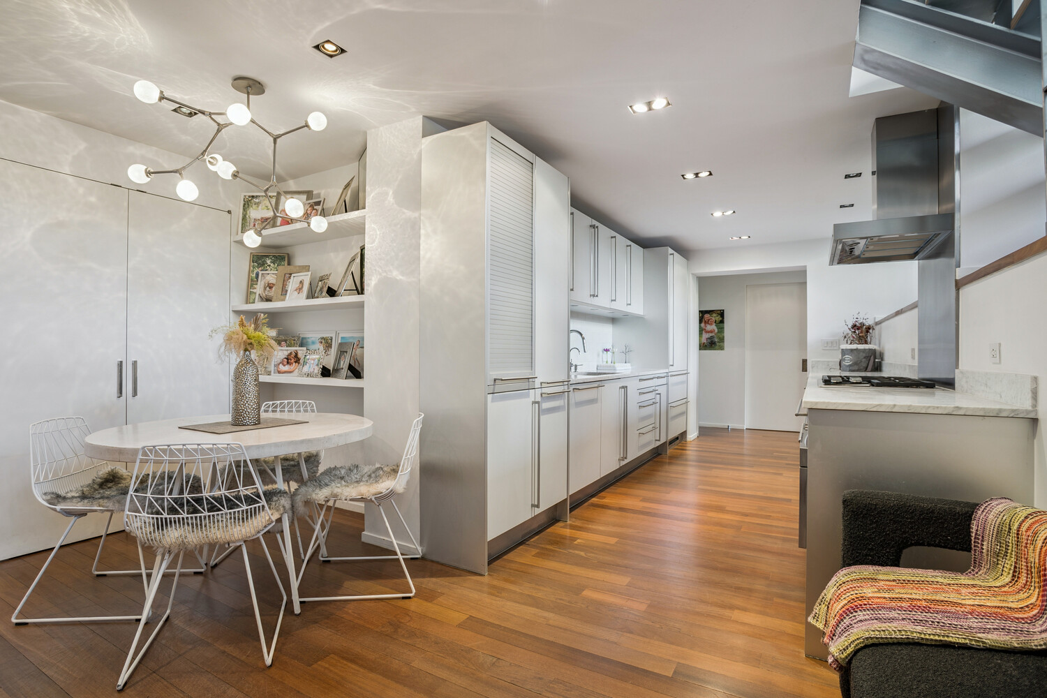 77 Bleecker Street, Unit 307 Manhattan, NY 10012 - Photo 5 of 14 a kitchen with stainless steel appliances kitchen island granite countertop a table chairs sink and cabinets