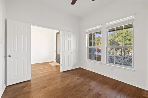 an empty room with wooden floor and windows