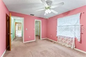 an empty room with chandelier fan and windows