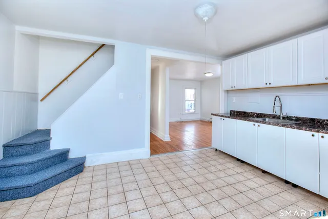 a kitchen view with staircase and white cabinets