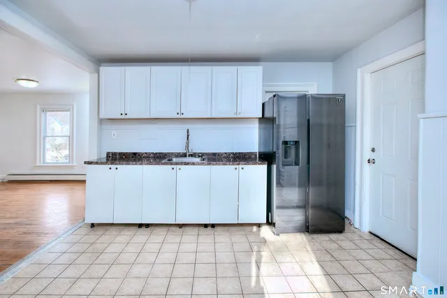 a kitchen with white cabinets and refrigerator
