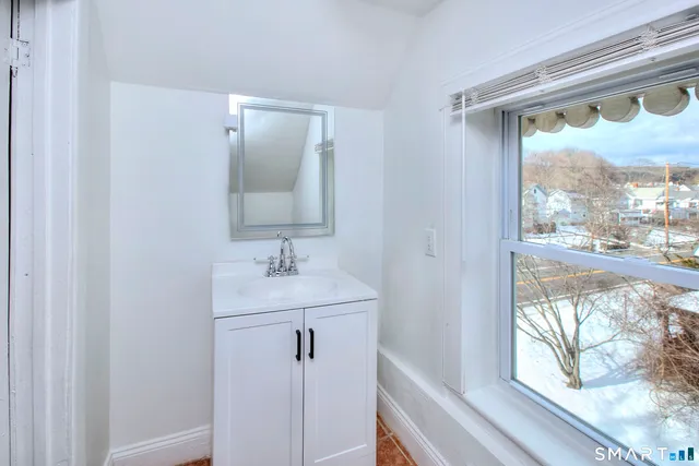 a bathroom with a sink mirror and a window