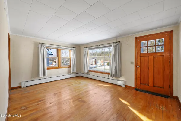 a view of an empty room with wooden floor and a window