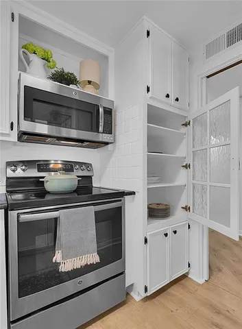 a kitchen with kitchen island a counter top a stove a chimney a large window and wooden floor