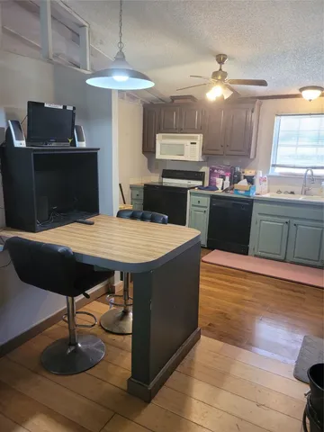 a kitchen with stainless steel appliances kitchen island granite countertop a table chairs and a wooden floor