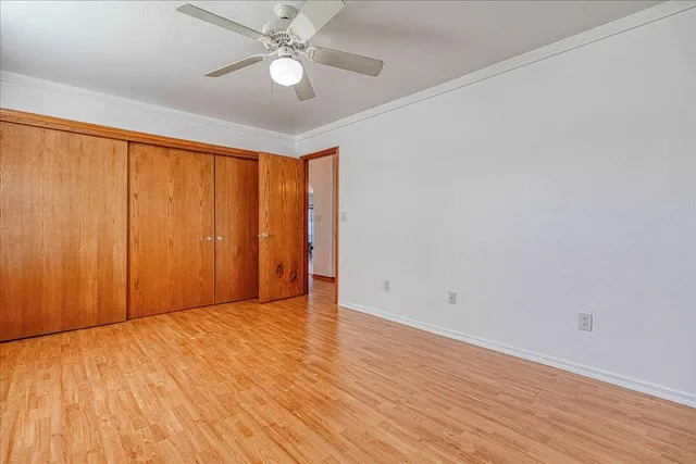 an empty room with wooden floor fan and windows