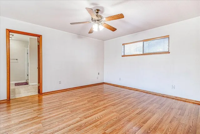 an empty room with wooden floor and ceiling fan