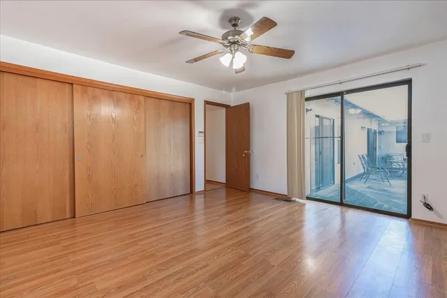 a view of an empty room with a window and wooden floor