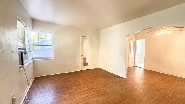 a view of an empty room with wooden floor and a window