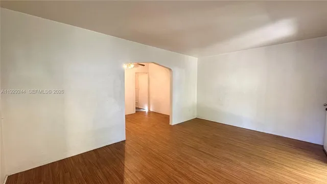 an empty room with wooden floor and natural light