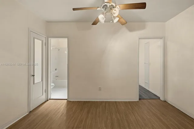 an empty room with wooden floor chandelier fan and closet area
