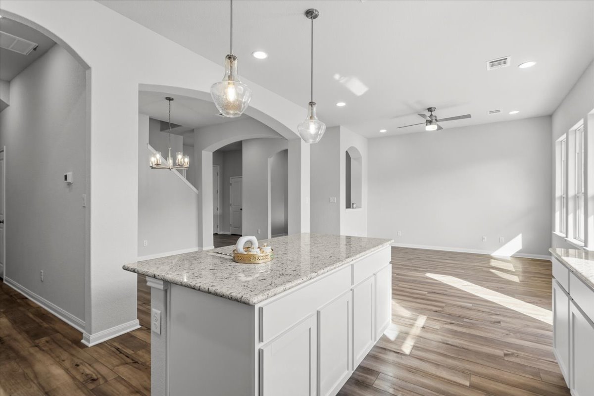 8513 Wellspring Loop Round Rock, TX 78665 - Photo 9 of 40 Kitchen featuring arched walkways, light stone countertops, and dark wood finished floors